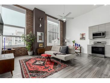 Bright living room features large windows, hardwood floors, exposed brick, and modern decor at 720 16Th St # 505, Denver, CO 80202