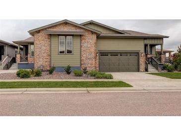 Charming home with a stone and siding exterior, two-car garage, and meticulously landscaped front yard at 7029 Sagerock St, Castle Pines, CO 80108