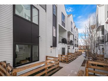 Modern townhouse exterior with black framed windows, white siding, a small patio area, and lush lawn at 1169 S Reed Way, Lakewood, CO 80232