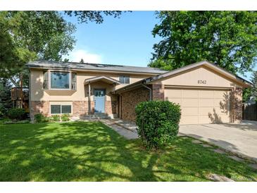 Charming two-story home with manicured lawn, brick accents, attached garage, and inviting blue front door at 6742 Cole Cir, Arvada, CO 80004