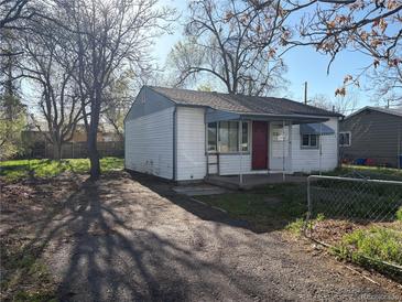 Charming single story home featuring a red front door, light blue trim and siding, set back from the street in an overgrown yard at 7810 Pontiac St, Commerce City, CO 80022