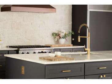 Modern kitchen featuring dark cabinetry, stainless steel appliances, marble countertops and gold fixtures at 4121 S Cherry St, Cherry Hills Village, CO 80113