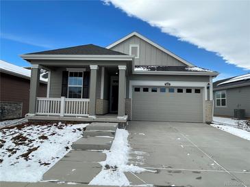 Charming single-Gathering home featuring a covered porch, gray siding, and a two-car garage at 5025 N Quemoy St, Aurora, CO 80019