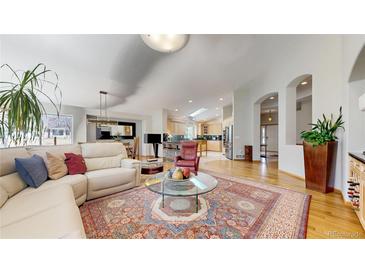 Spacious living room featuring hardwood floors, an area rug, and an open floor plan connecting to the kitchen at 9559 Brook Hill Ln, Lone Tree, CO 80124