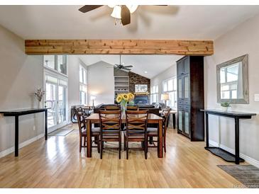 Open dining area with wood floors, large dining table, and seamless flow to a living room with fireplace at 7877 S University Way, Centennial, CO 80122