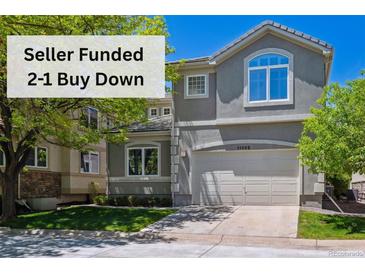 Charming two-story home with a neutral-toned exterior, arched window, attached garage, and well-maintained lawn at 11969 E Lake Cir, Greenwood Village, CO 80111