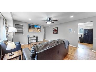 Comfortable living room featuring a plush leather sofa, ceiling fan, and hardwood flooring at 1720 Mable Ave, Denver, CO 80229