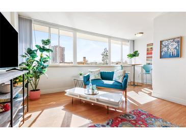 Bright living room featuring a comfortable blue sofa, large windows, and stylish decor at 1196 N Grant St # 405, Denver, CO 80203