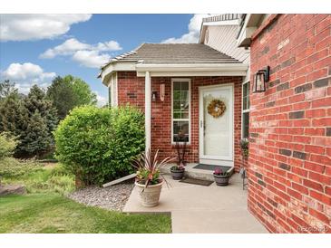 Charming brick home entrance with a white door, wreath, and beautiful landscaping at 9441 Southern Hills Cir, Lone Tree, CO 80124