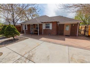 Charming brick home featuring a spacious front patio and well-manicured yard at 3021 Grape St, Denver, CO 80207