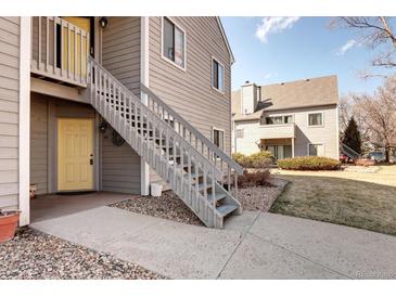 Charming condo with a yellow front door and grey wood siding at 3600 S Pierce St # 106, Lakewood, CO 80235