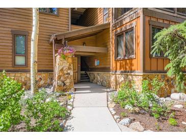 Inviting entrance with stone accents, wood siding, and a flower basket detail leads into the building at 180 Broken Lance Dr # 14, Breckenridge, CO 80424