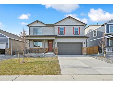 Charming two-story home featuring a covered porch, gray siding, red shutters, and a two-car garage at 27684 E Byers Ave, Aurora, CO 80018