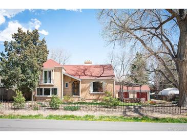 Charming brick home with a red roof, mature trees, and a wrought iron fence at 2084 Bell Ct, Lakewood, CO 80215