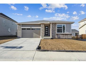 Charming single-story home featuring stone accents, a two-car garage, and a well-lit entrance at 6974 E 126Th Dr, Thornton, CO 80602