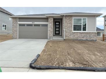 Charming single-story home featuring a modern front door, grey garage door, and a well-lit driveway at 6974 E 126Th Dr, Thornton, CO 80602