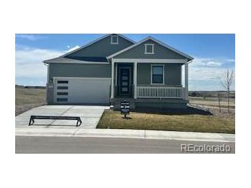 Charming single-story home with a welcoming front porch and a well-manicured lawn on a sunny day at 42986 Colonial Trl, Elizabeth, CO 80107