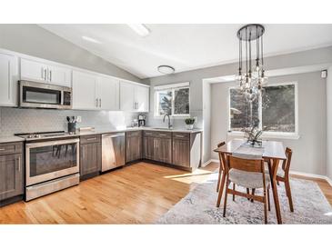 Bright kitchen features stainless steel appliances, two-tone cabinets, and wood floors with a dining nook at 2488 W 111Th Pl, Denver, CO 80234