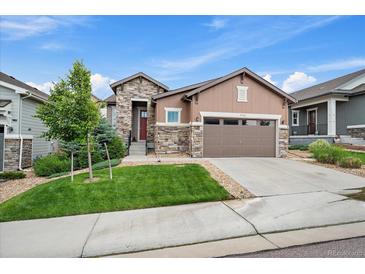Charming home featuring manicured lawn, stone accents, and a convenient two-car garage, all under a beautiful blue sky at 3336 Goodyear St, Castle Rock, CO 80109