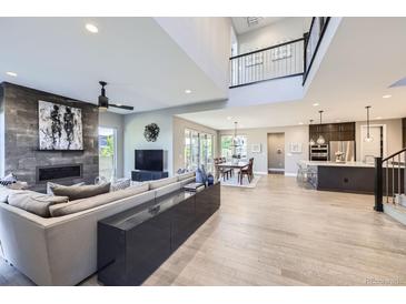 Expansive open-concept living room featuring fireplace, modern decor, and seamless flow to the dining and kitchen areas at 6005 Beeler St, Denver, CO 80238