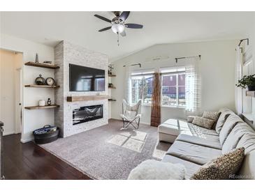 Bright living room featuring a fireplace, ceiling fan, and lots of natural light through the windows at 1421 Rustic Dr, Longmont, CO 80504