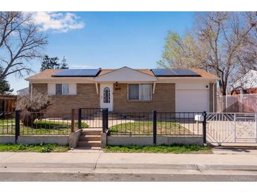 Charming brick ranch-style home with a gated front yard and solar panels on the roof at 5519 Tucson St, Denver, CO 80239