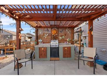 Outdoor patio with a wooden pergola, custom grill station, and cozy seating area at 2320 Morningview Ln, Castle Rock, CO 80109