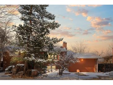 Charming home exterior with a red brick facade, attached two-car garage, and mature trees covered in snow at 255 Iroquois Dr, Boulder, CO 80303