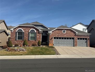 Charming brick home featuring a well-manicured front yard and an attached three-car garage at 20715 Bridlewood Ln, Parker, CO 80138