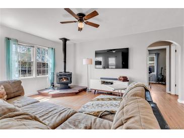 Cozy living room featuring a wood-burning stove, ceiling fan, hardwood floors, and a comfortable sofa at 15205 W 43Rd Ave, Golden, CO 80403