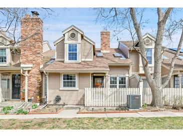 Charming townhome with a brick chimney and a well-maintained front yard and white picket fence at 14204 E Radcliff Cir, Aurora, CO 80015