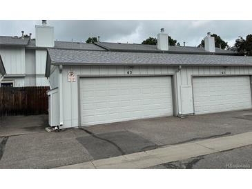 Attached one car garage with white door and adjacent parking in front of the home at 10320 E Jewell Ave # 63, Aurora, CO 80247