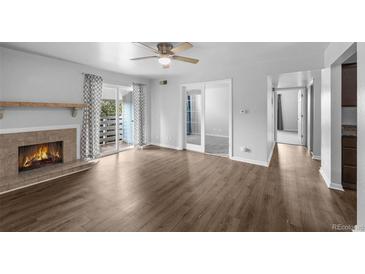 Spacious living room featuring a fireplace, ceiling fan, balcony, and hardwood floors at 7665 E Eastman Ave # 301A, Denver, CO 80231