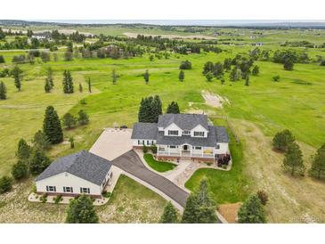 Stunning aerial view of the charming home with a separate garage surrounded by a vast green field at 3973 Palmer Ridge Dr, Parker, CO 80134