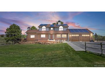 Charming brick two-story home featuring an attached garage, solar panels, and a beautifully manicured lawn at 9025 Rocky Mountain Ln, Parker, CO 80138