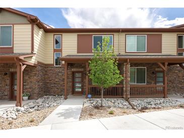 Attractive townhome featuring a stone facade, covered porch, and low maintenance landscaping with neutral color palettes at 11228 Bella Vita Dr, Broomfield, CO 80020