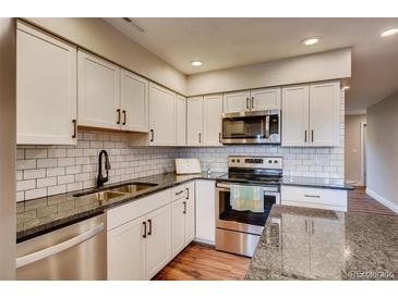 Bright kitchen featuring white cabinets, stainless steel appliances, and stylish subway tile backsplash at 7110 S Gaylord St # L7, Centennial, CO 80122