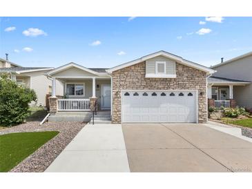Charming home featuring a stone facade, well-manicured lawn, and a spacious two-car garage at 2034 Espana Way, Aurora, CO 80011