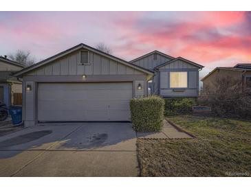 Charming home exterior with a two-car garage, front yard and a beautiful sky in the background at 18890 E Carmel Cir, Aurora, CO 80011