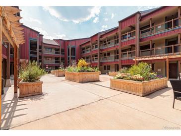 Beautiful condo courtyard featuring planter boxes with greenery, red exterior walls, and community space at 107 N Harris St # 306, Breckenridge, CO 80424