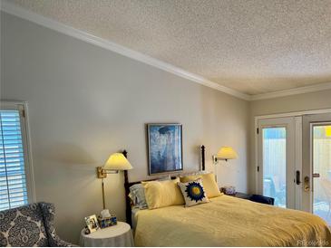 Cozy bedroom featuring a sunny yellow quilted bedspread and natural light from the door with access to the outdoors at 8040 E Dartmouth Ave # 16, Denver, CO 80231