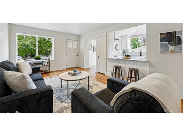 Inviting living room with hardwood floors, gray couches, white door, and a view to the kitchen at 3346 W 33Rd Ave, Denver, CO 80211