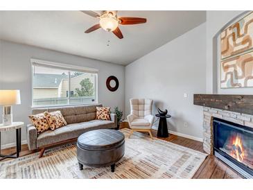 Cozy living room with decorative fireplace, gray sofa, and a ceiling fan at 2132 Boise Ct, Longmont, CO 80504