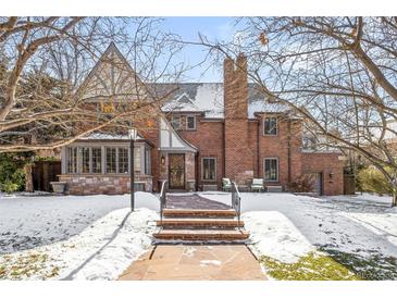 Beautiful brick home with manicured lawn and inviting entryway, framed by mature trees and winter's touch at 2020 E 4Th Ave, Denver, CO 80206