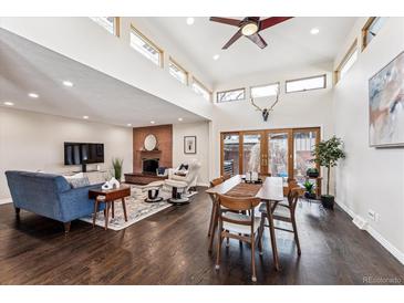 Spacious living room featuring a brick fireplace, vaulted ceilings, and modern furnishings at 7642 S Ames Way, Littleton, CO 80128
