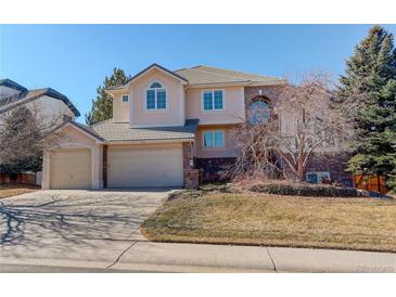 Charming two-story home featuring a three-car garage, and manicured landscaping on a sunny day at 9554 E Hidden Hill Ln, Lone Tree, CO 80124