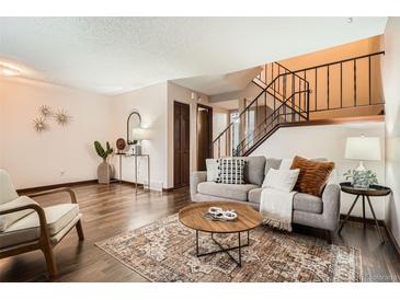 Inviting living room features hardwood floors, neutral paint, and access to a staircase at 444 Vance St, Lakewood, CO 80226