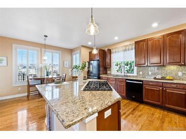 Well-lit kitchen with granite countertops, stainless steel appliances, and hardwood floors at 395 Winterthur Way, Highlands Ranch, CO 80129