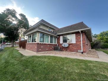 Charming brick home featuring a sunroom, manicured lawn, and mature trees at 9762 Appletree Pl, Thornton, CO 80260