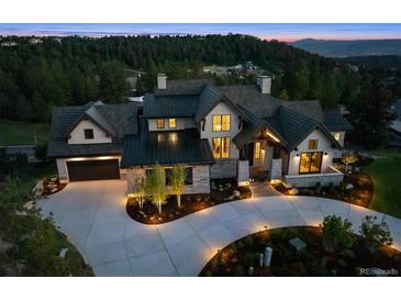 Stunning home exterior featuring a circular drive, stone accents, and meticulous landscaping at twilight at 1118 Northwood Ln, Castle Rock, CO 80108